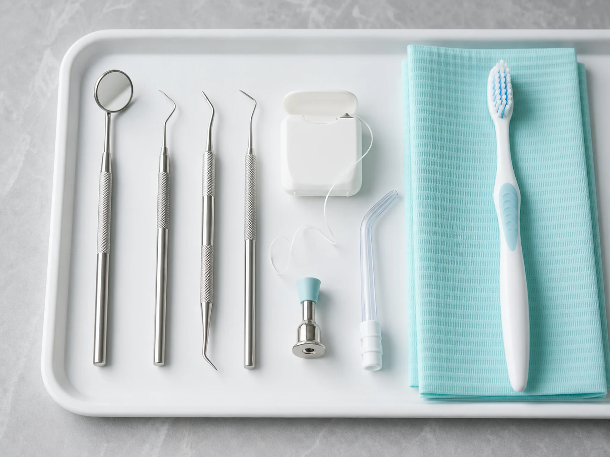 Preventive dental instruments, floss, toothbrush, and fresh bib arranged on a clean tray